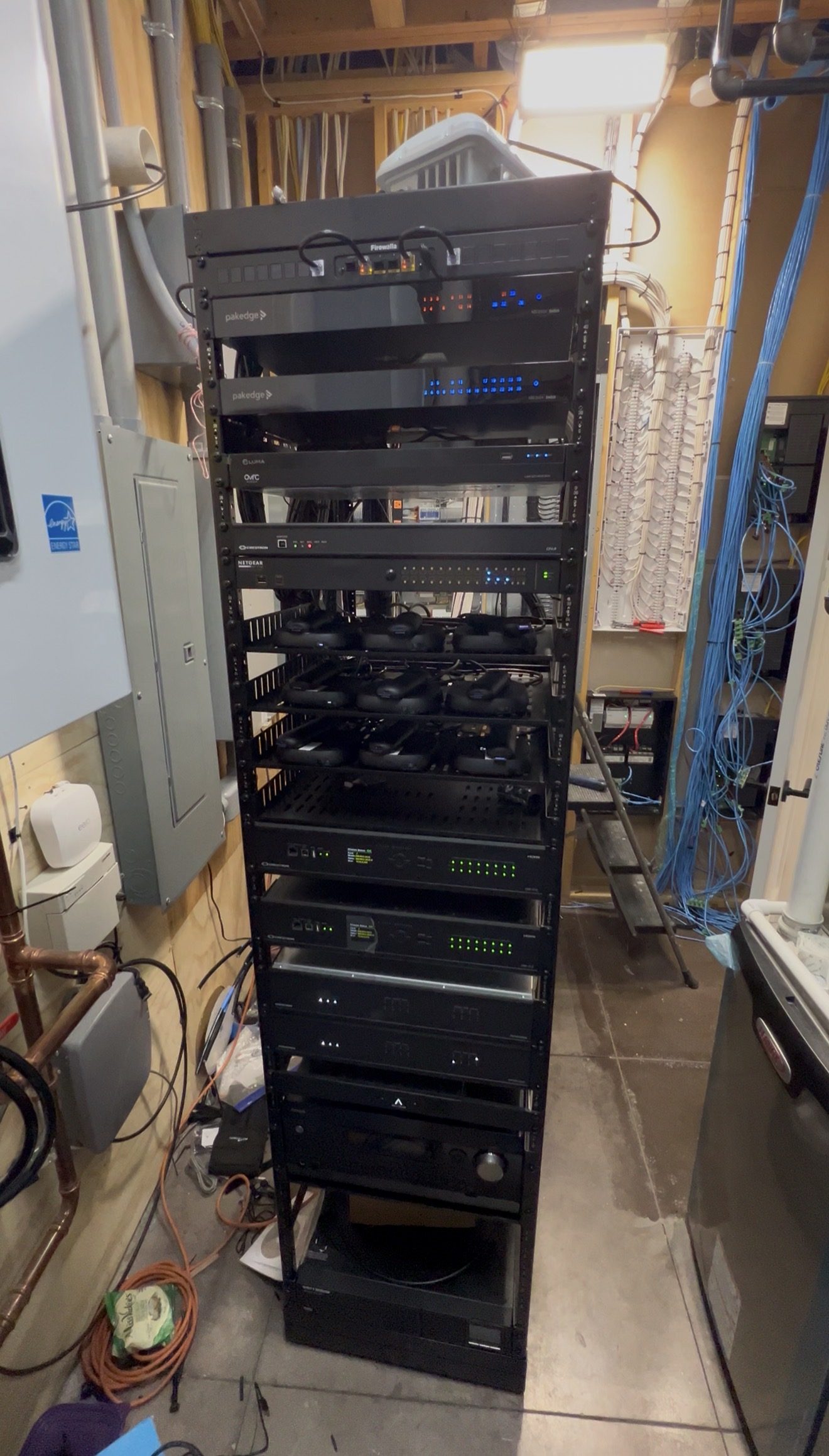 Full-height equipment rack with Crestron, Pakedge, and Luma networking and automation gear
